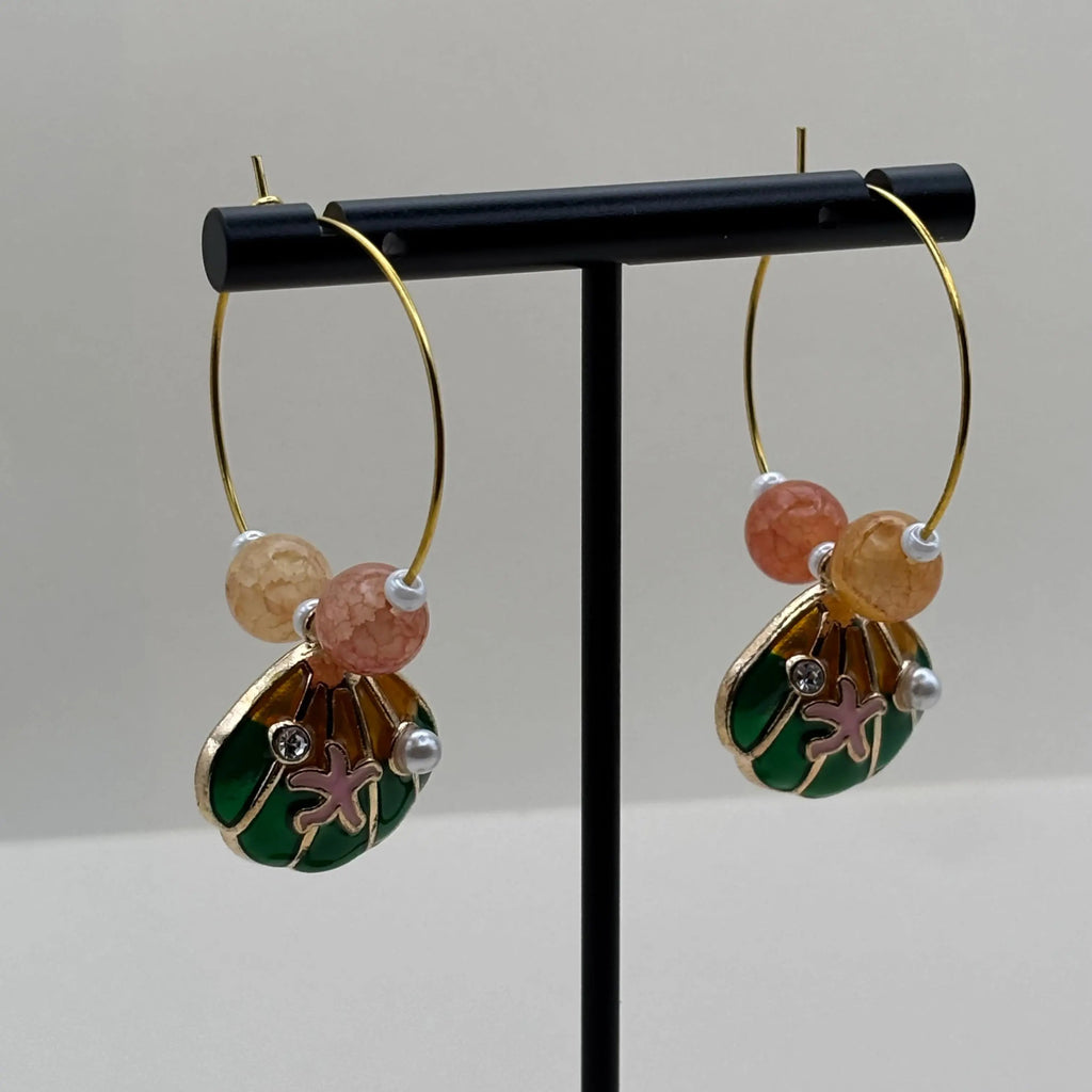 Des boucles d'oreilles créoles dorées avec breloque coquille Saint Jacques peinte et deux perles