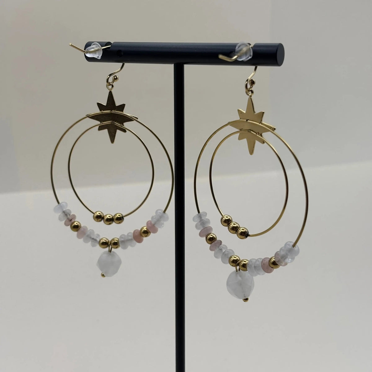 Des boucles d’oreilles créoles dorées avec deux cercles ornés de pierres blanches et perles dorées