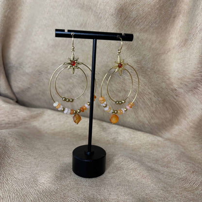 Boucles d’oreilles créoles dorées avec deux cercles ornés de pierres orangées et perles dorées vendues sur le site internet prêtes à briller