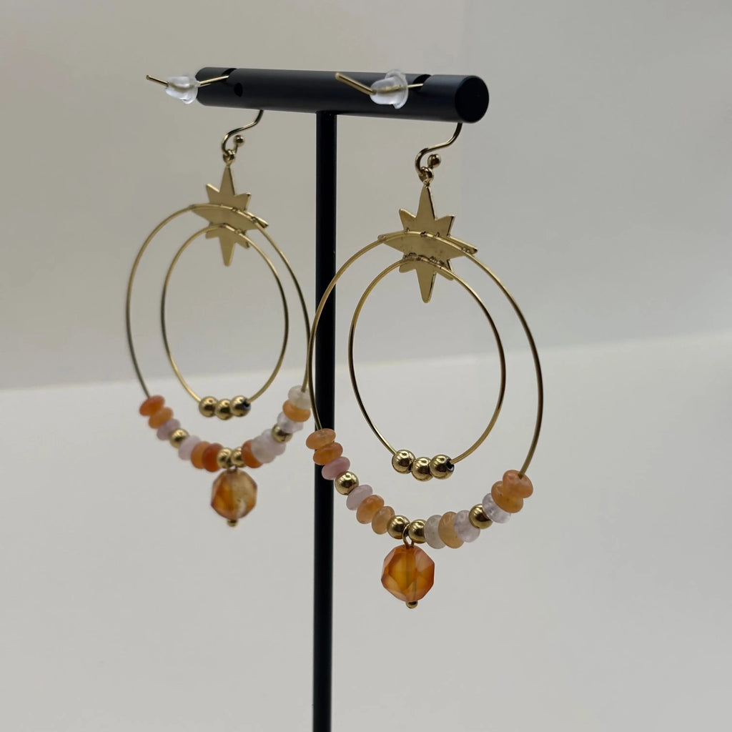 Des boucles d’oreilles créoles dorées avec deux cercles ornés de pierres rouges et perles dorées