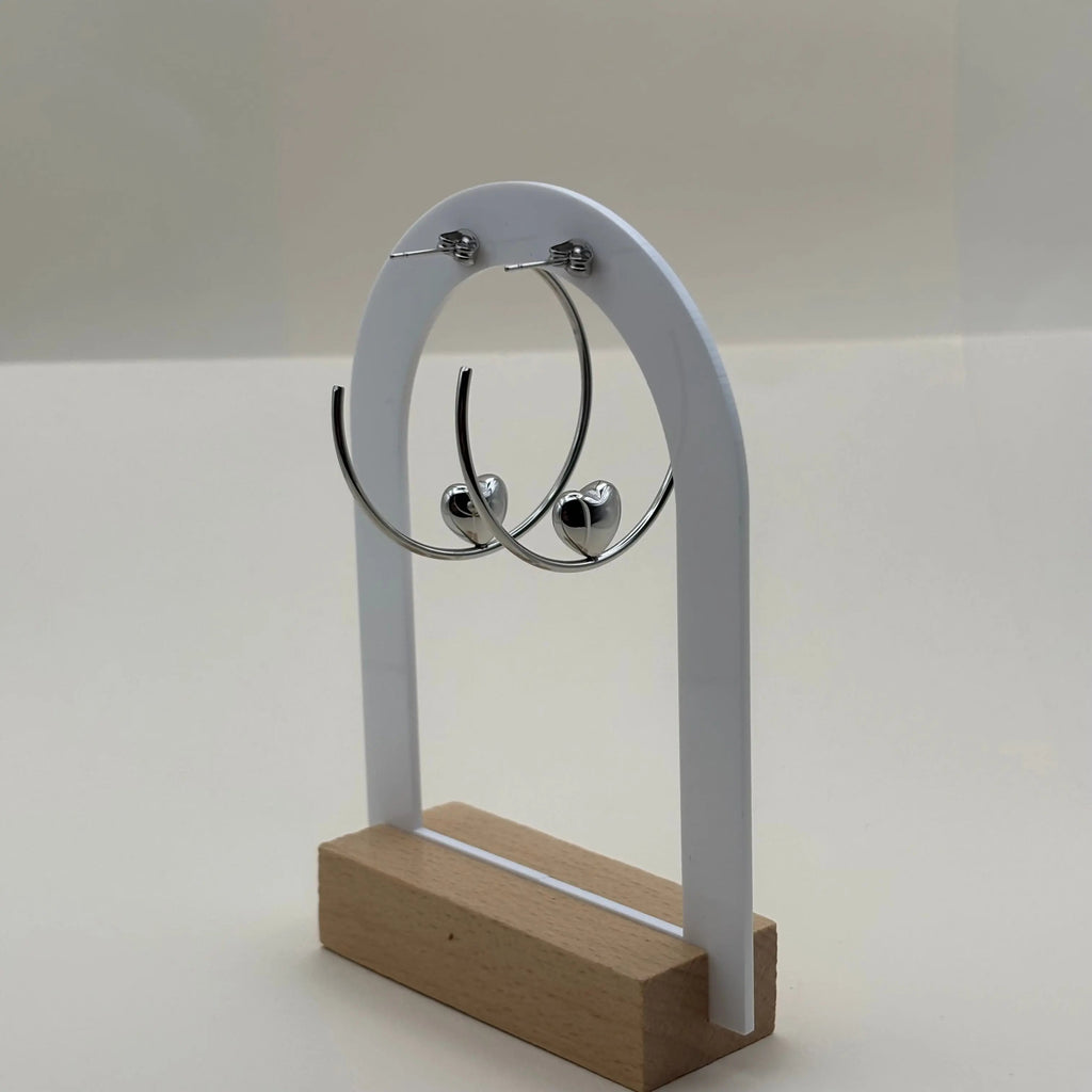 Une paire de boucles d'oreilles créoles avec motif en cœur argenté en acier 