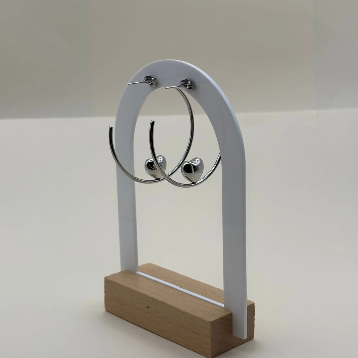 Une paire de boucles d'oreilles créoles avec motif en cœur argenté en acier 