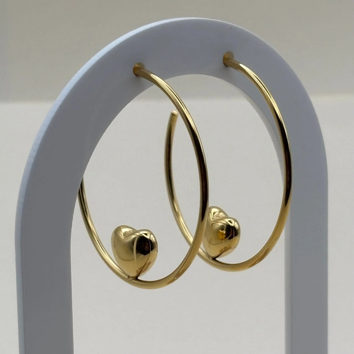 Vue de près de boucles d'oreilles créoles avec motif en cœur doré en acier inoxydable