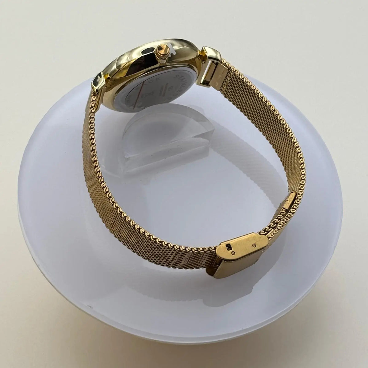 Vue de coté d'une montre pour femme bracelet doré cadran blanc irisé orné de strass sur le pourtour