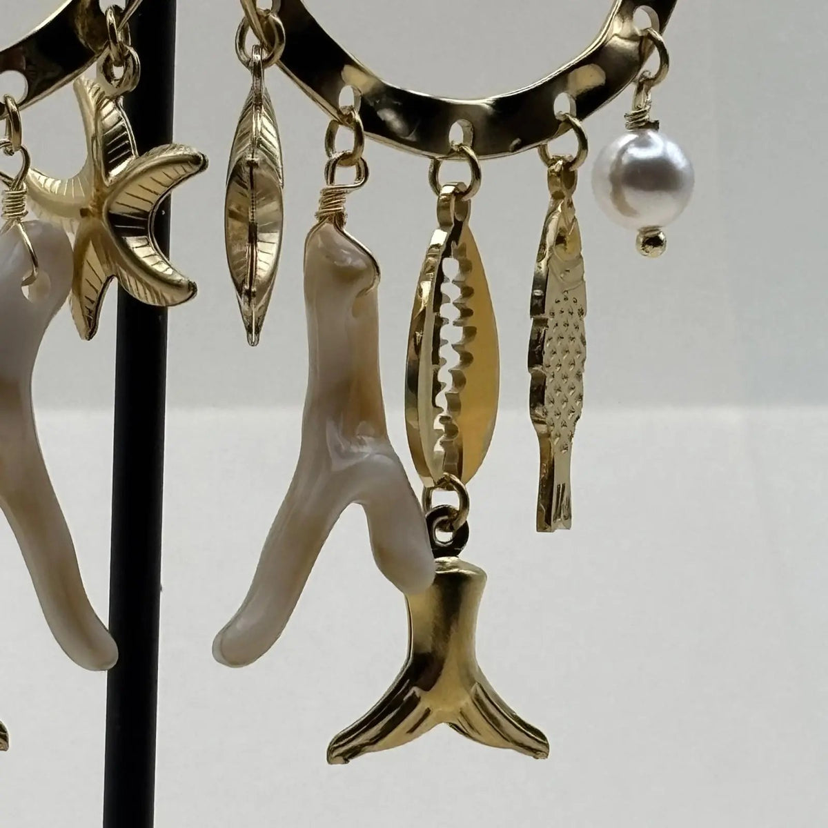 Des boucles d'oreilles dorées avec anneau et breloques blanc étoile de mer coquillage