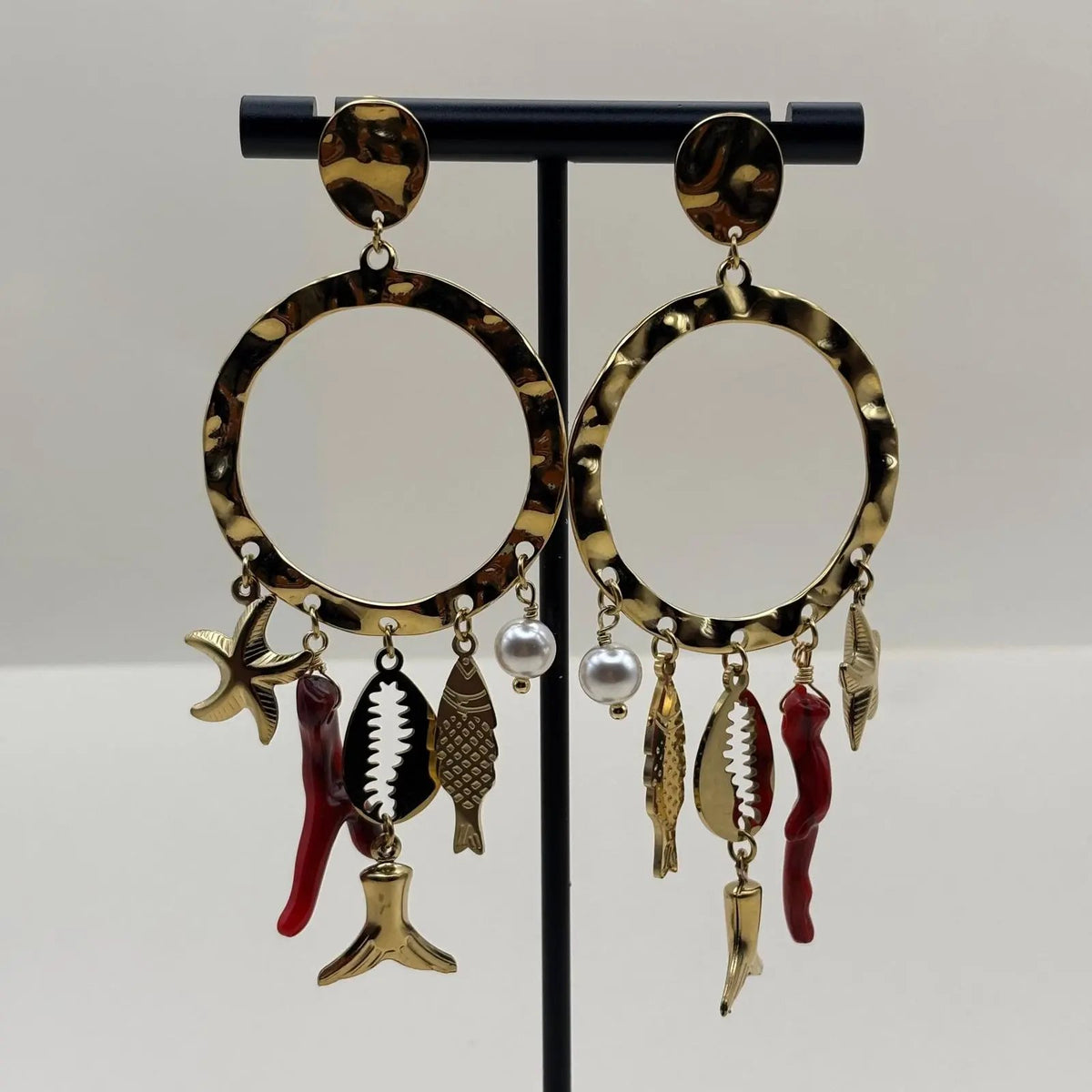 Des boucles d'oreilles dorées avec anneau et breloques rouge étoile de mer coquillage
