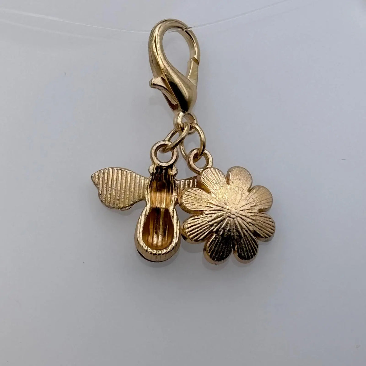 Bijou à accrocher de couleur dorée avec breloque abeille et marguerite blanche