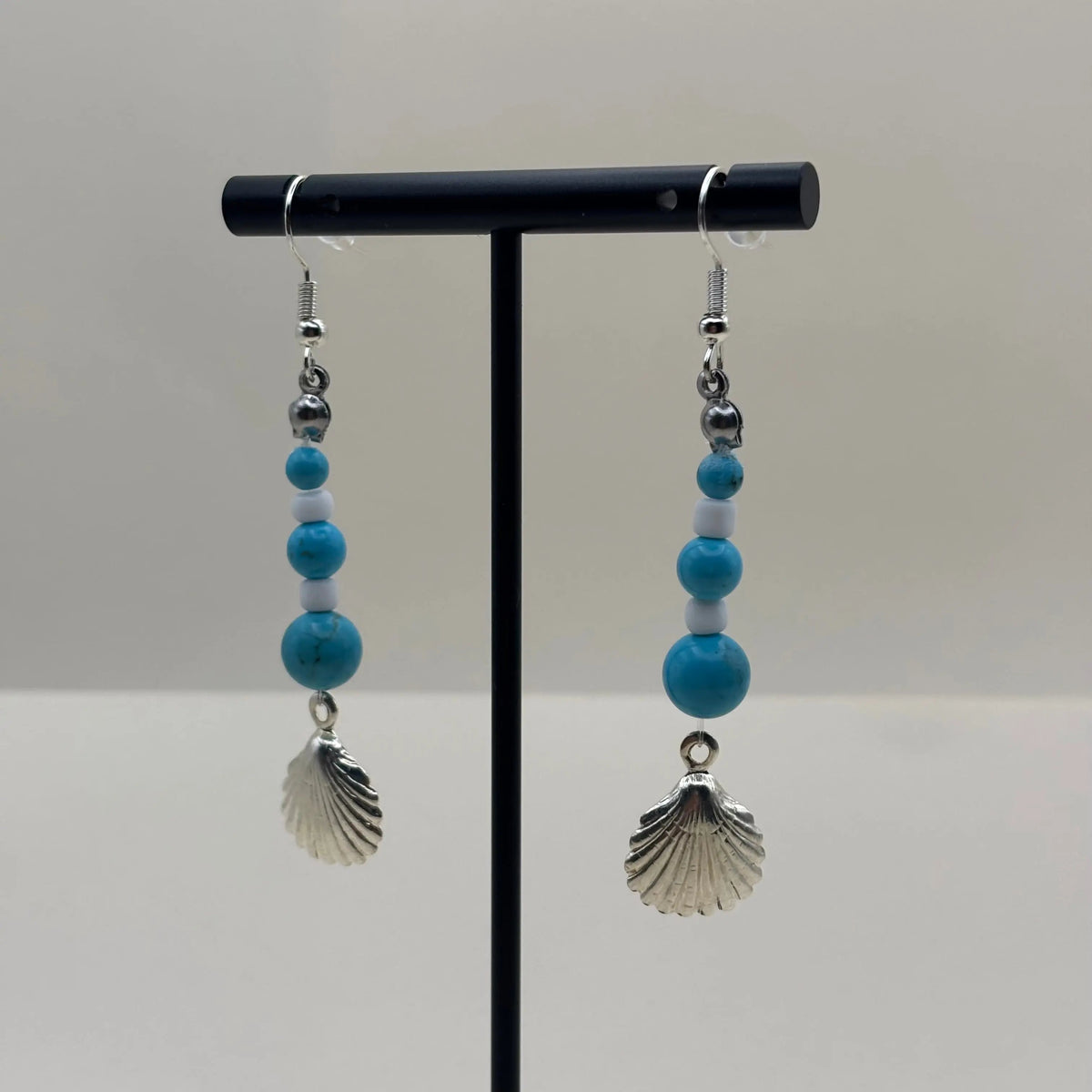 Des boucles d’oreilles pendantes avec attache argentée avec breloque coquille St Jacques et perles pastels bleues 
