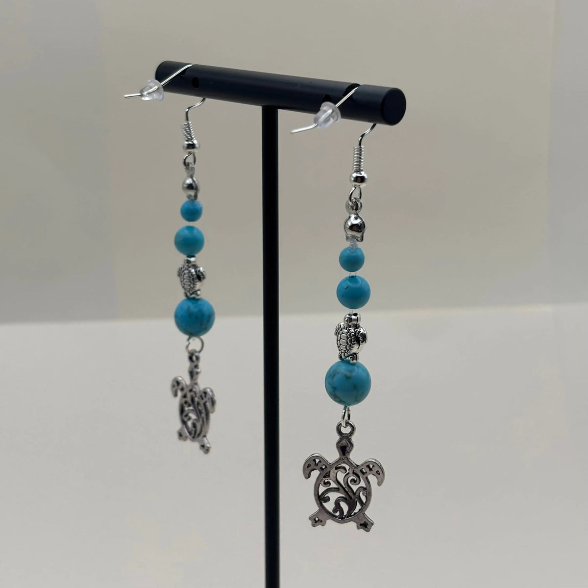 Des boucles d’oreilles pendantes avec attache argentée avec breloque tortues et perles pastels bleues 
