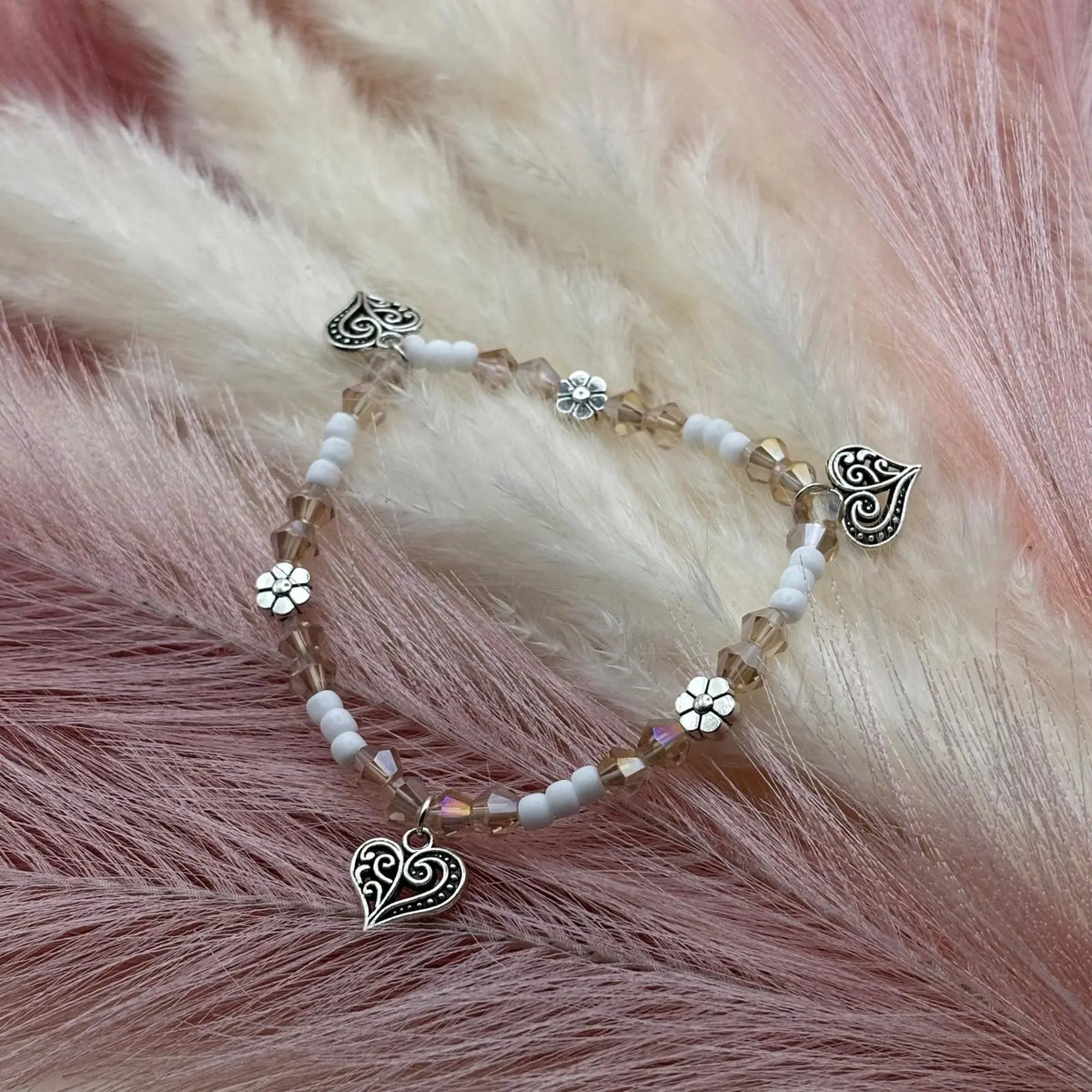 Bracelet en perles artisanal avec breloques cœurs et fleurs argentés
Perles de verre blanches sur élastique