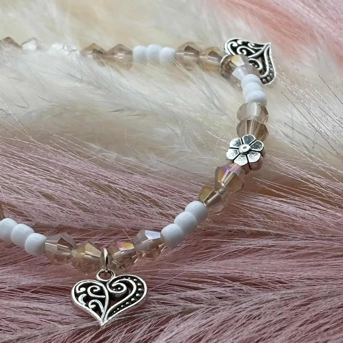 Vue de près d'un bracelet en perles artisanal avec breloques cœurs et fleurs argenté