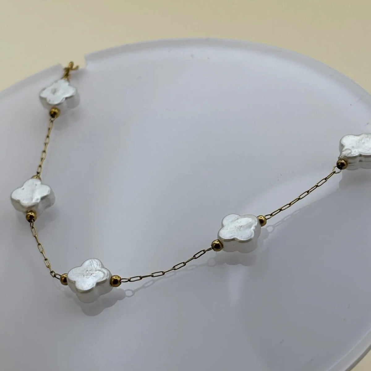 Bracelet doré avec de petits maillons et breloques en forme de trèfles blanc nacrés