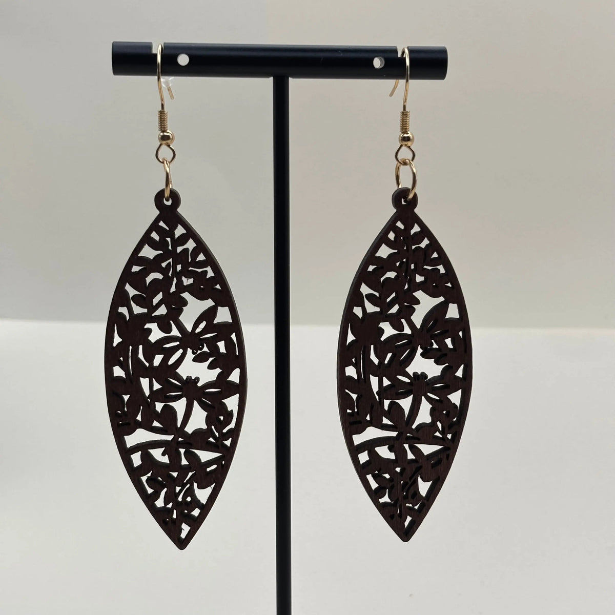 Des boucles d'oreilles avec attache dorée boucle en bois en forme de goutte d'eau et motif fleuri ajouré
