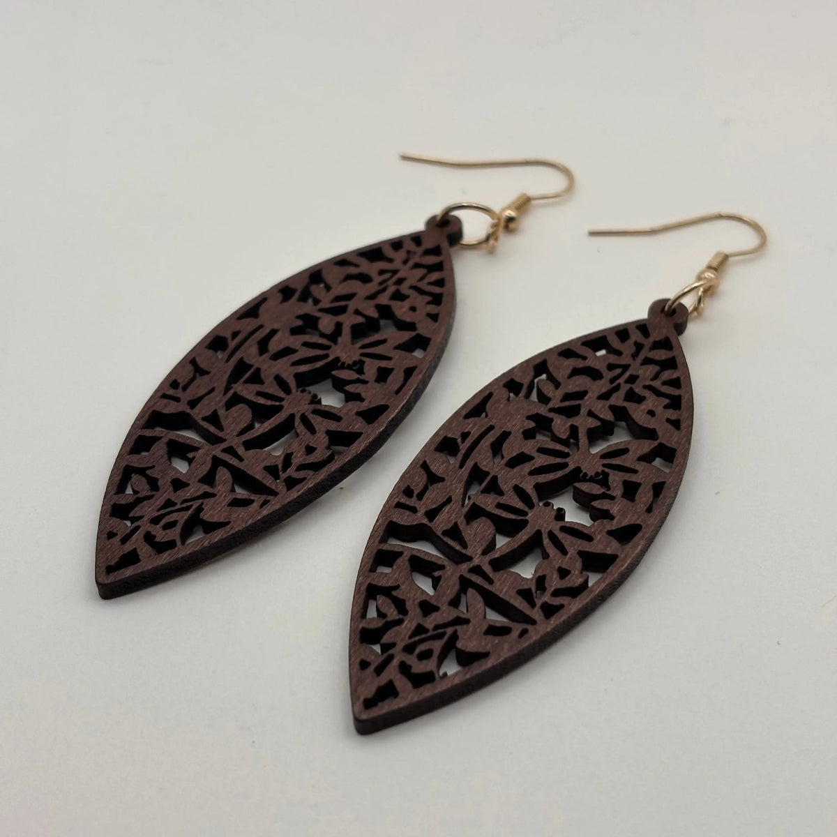 Une paire de boucles d'oreilles avec attache dorée boucle en bois en forme de goutte d'eau et motif fleuri ajouré