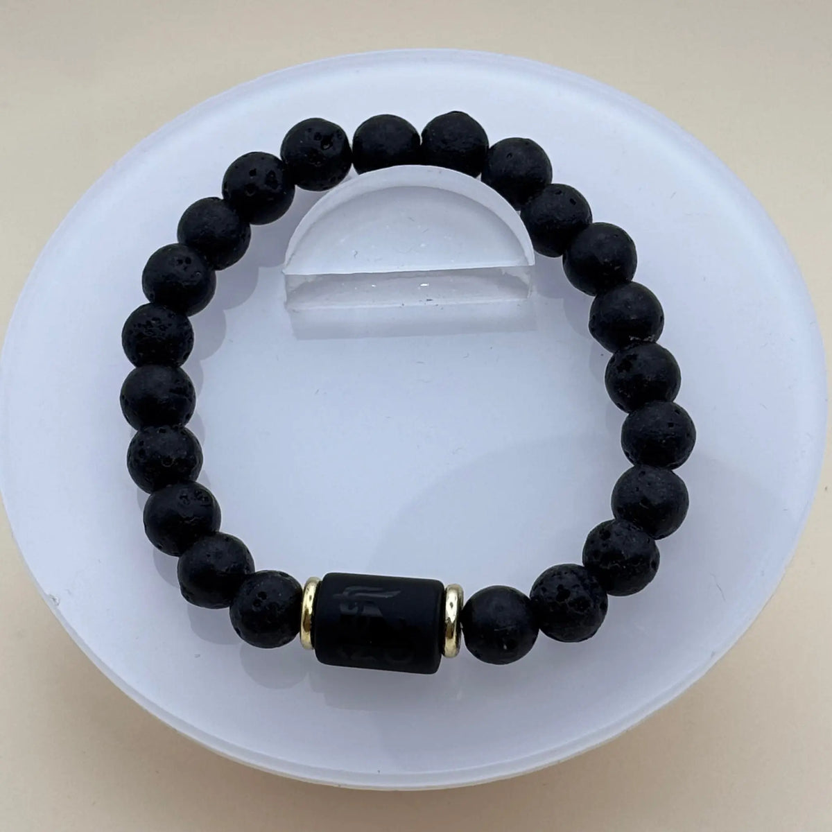 Bracelet en perles noires mates et lisses agrémenté d’un cylindre noir gravé encadré par deux anneaux dorés