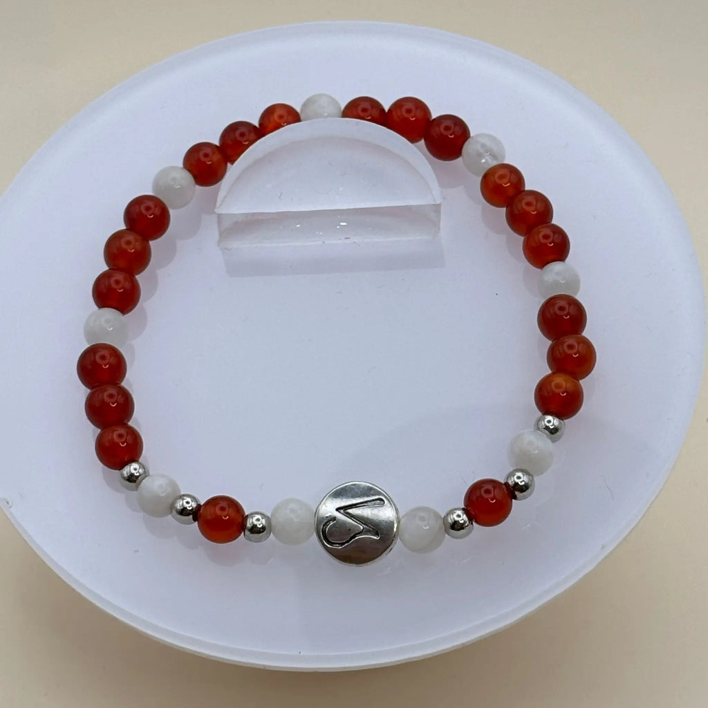 Bracelet alternant perles rouges et blanches avec un médaillon argenté gravé en façade