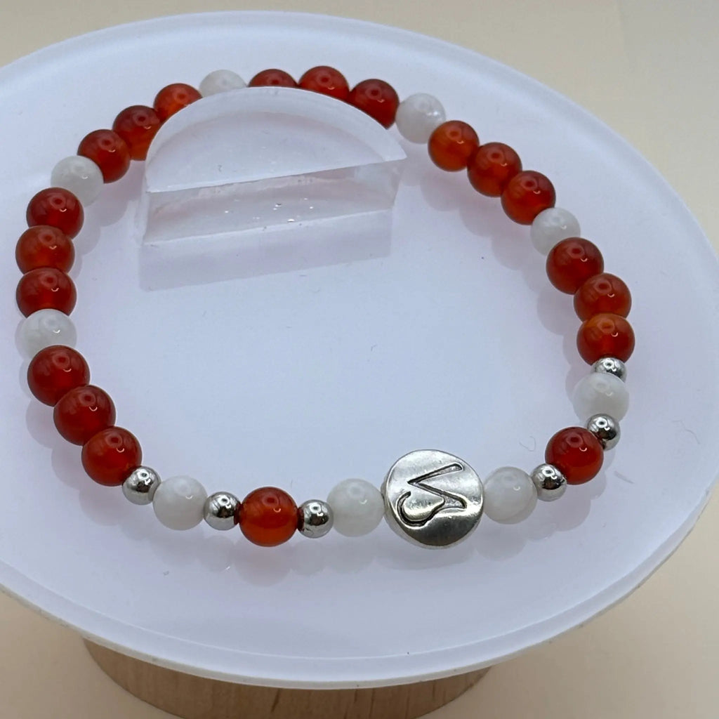 Bracelet alternant perles blanches et perles rouges avec un médaillon argenté gravé au centre