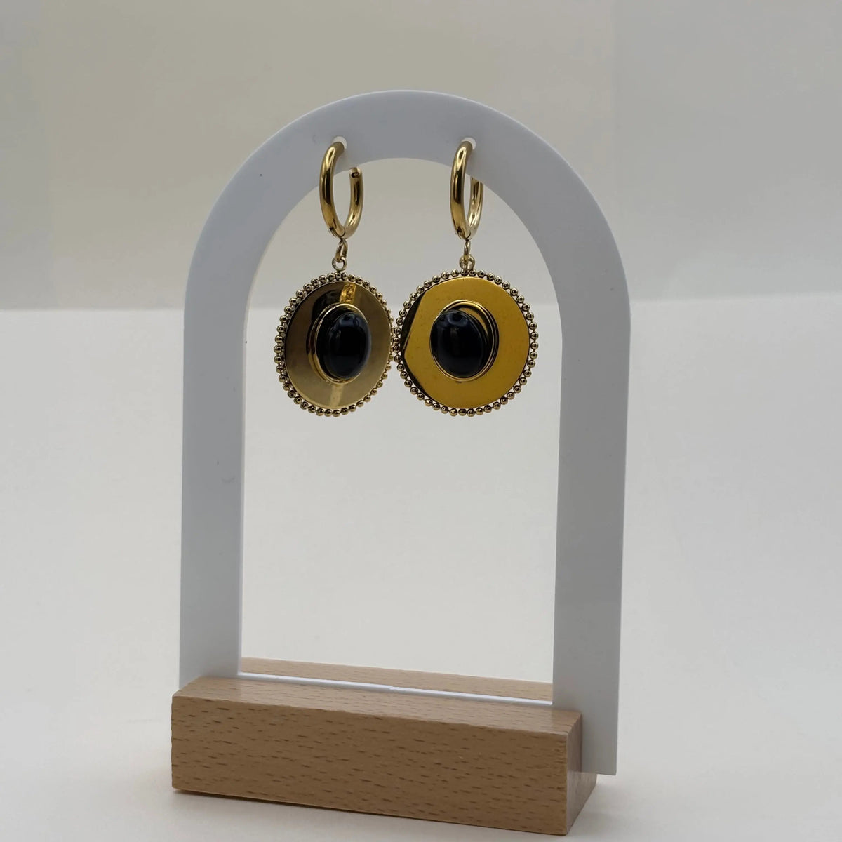Des boucles d'oreilles dorée pendantes avec cercle dorée et pierre façon camé noir