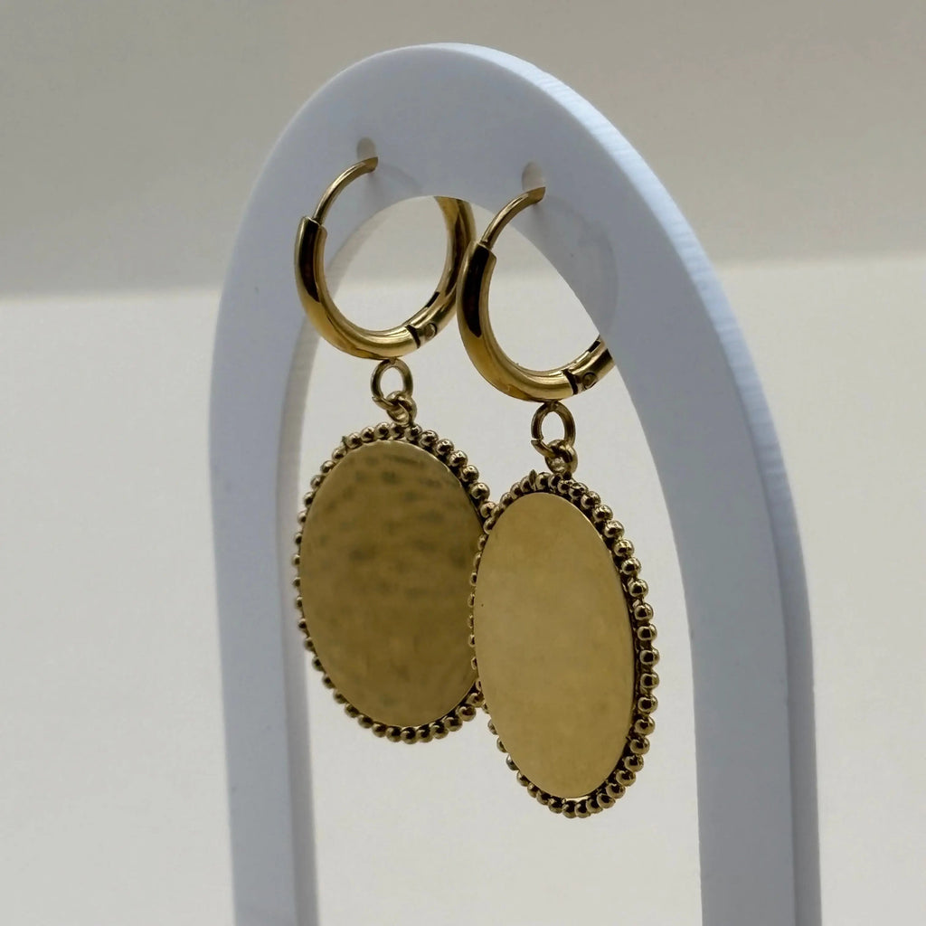 Des boucles d'oreilles dorée pendantes avec cercle dorée et pierre façon camé rose