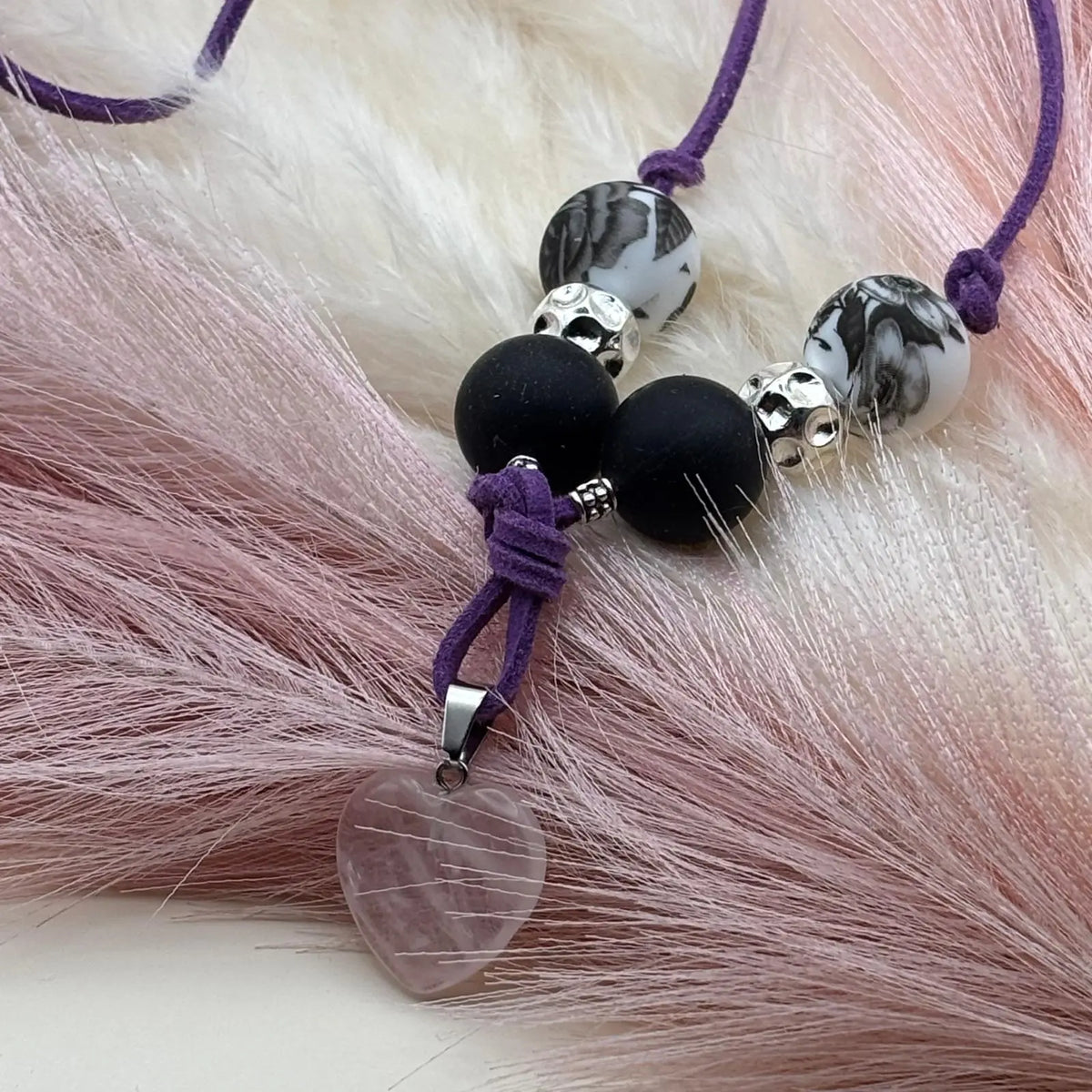 Vue de près d'un collier artisanal sur cordon de cuir violet  et pendentif cœur transparent