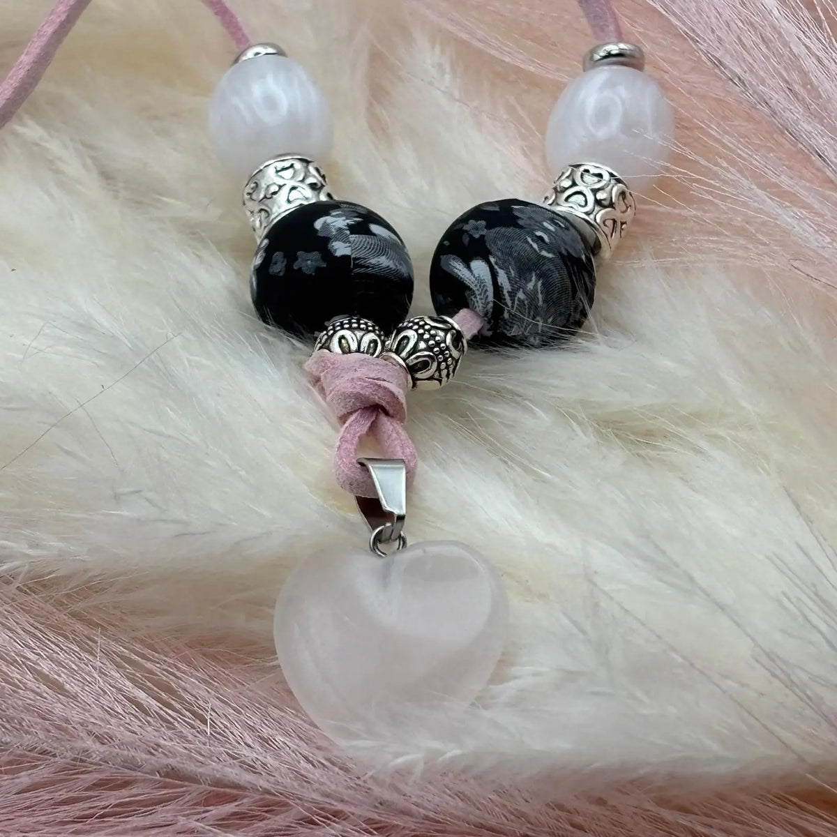 Vue de près d'un collier artisanal sur cordon de cuir rose pendentif cœur en verre perles de verre et acryliques