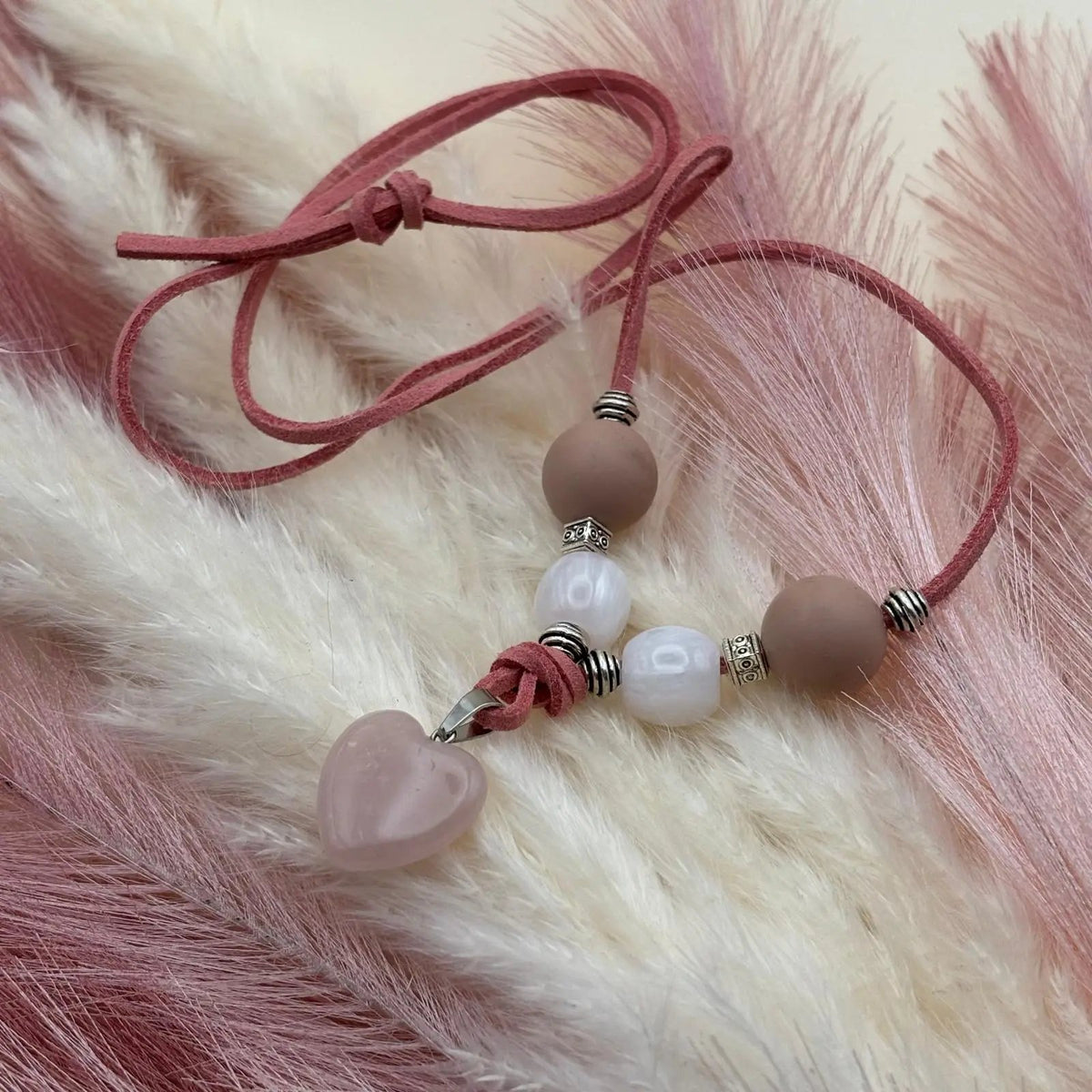 Vue de près d'un collier artisanal  sur cordon de cuir poudré avec pendentif en forme de cœur en verre perles verre et acrylique