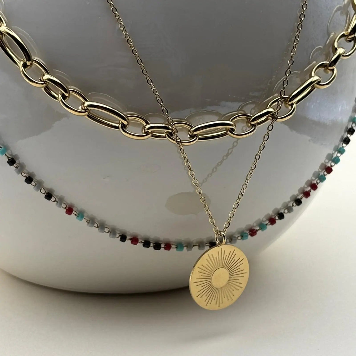 Un collier multirangs de couleur doré avec trois motifs différents soleil perles colorées chaines en acier inoxydable