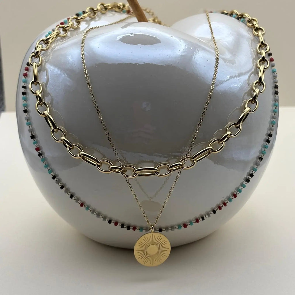 Un collier multirangs de couleur doré avec trois motifs différents soleil perles colorées chaines en acier inoxydable