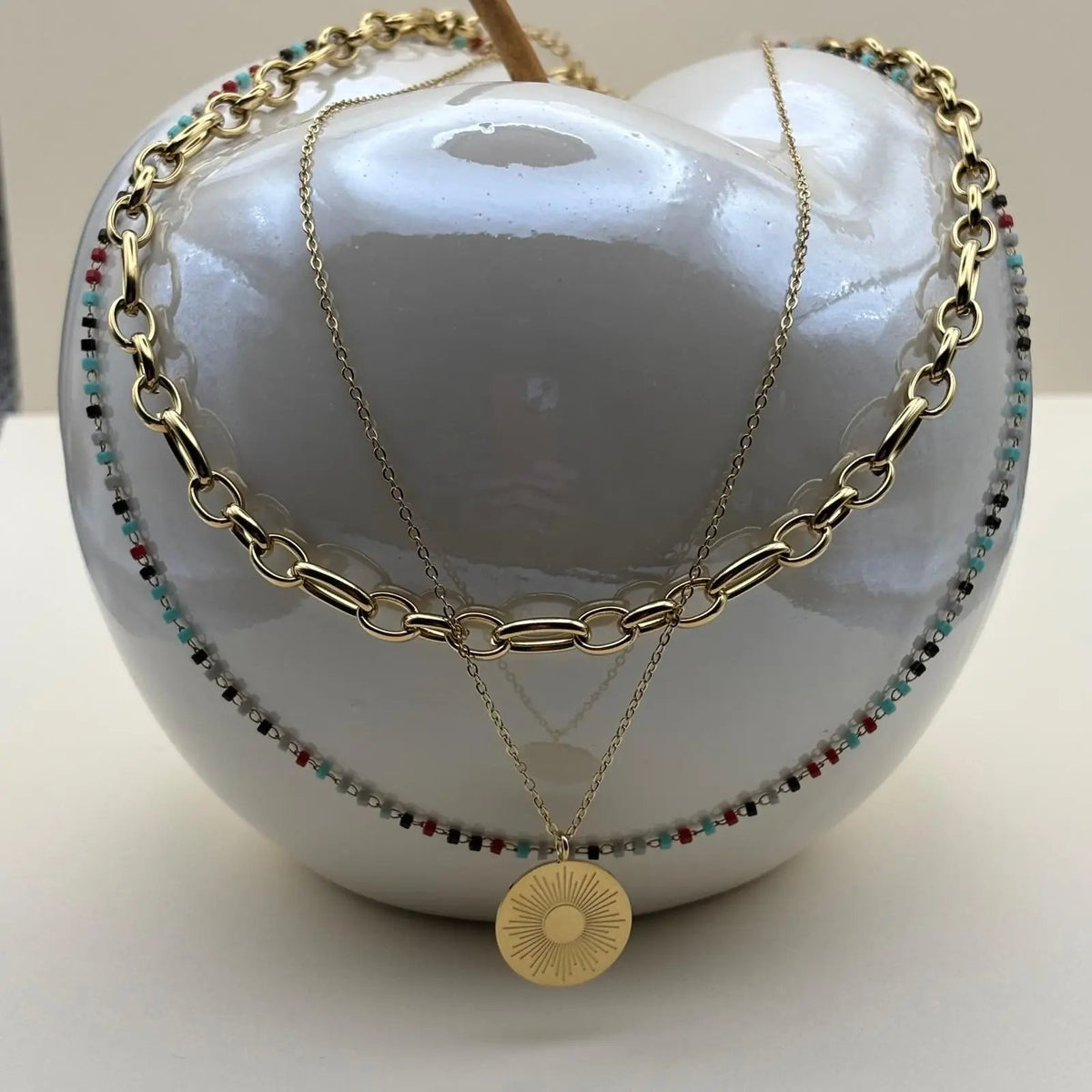 Un collier multirangs de couleur doré avec trois motifs différents soleil perles colorées chaines en acier inoxydable