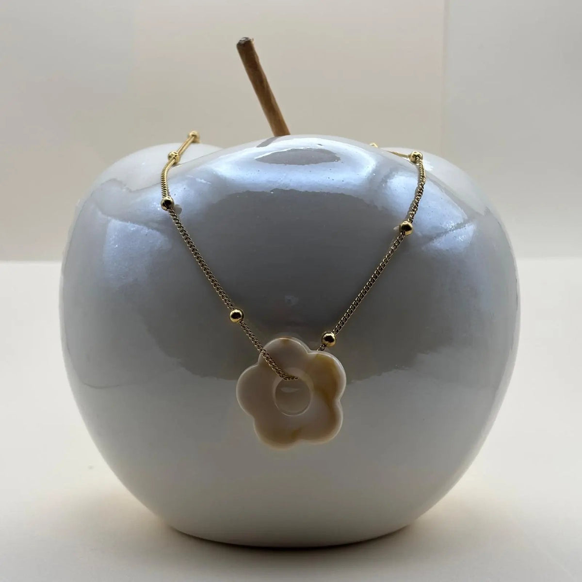 Un collier fantaisie avec une chainette dorée et perles dorées un pendentif fleur colorée écru en acier inoxydable