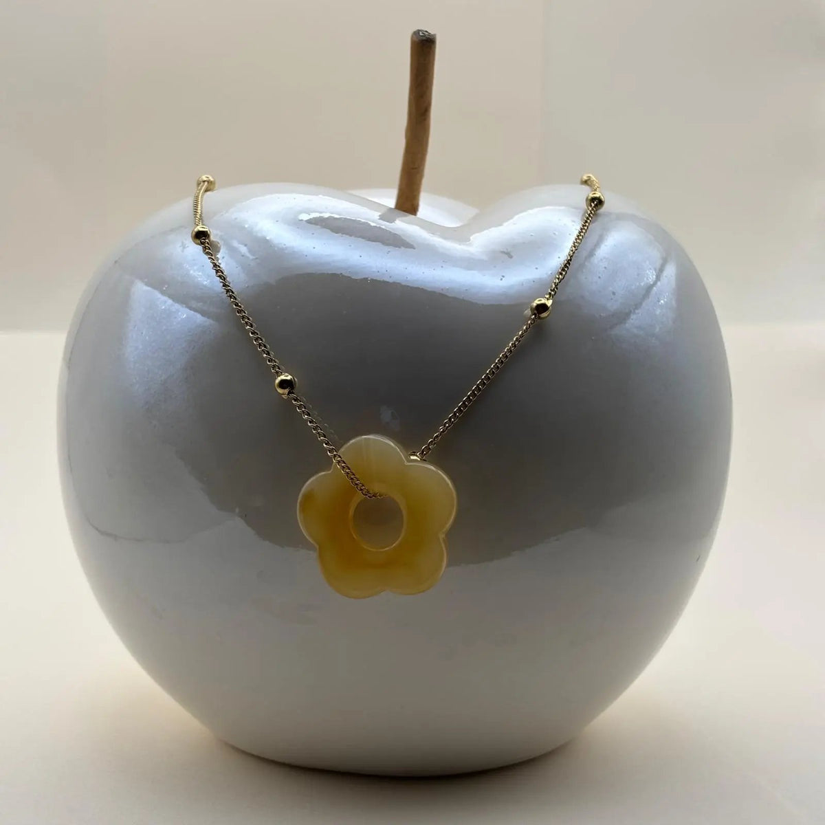 Un collier fantaisie avec une chainette dorée et perles dorées un pendentif fleur colorée jauneen acier inoxydable