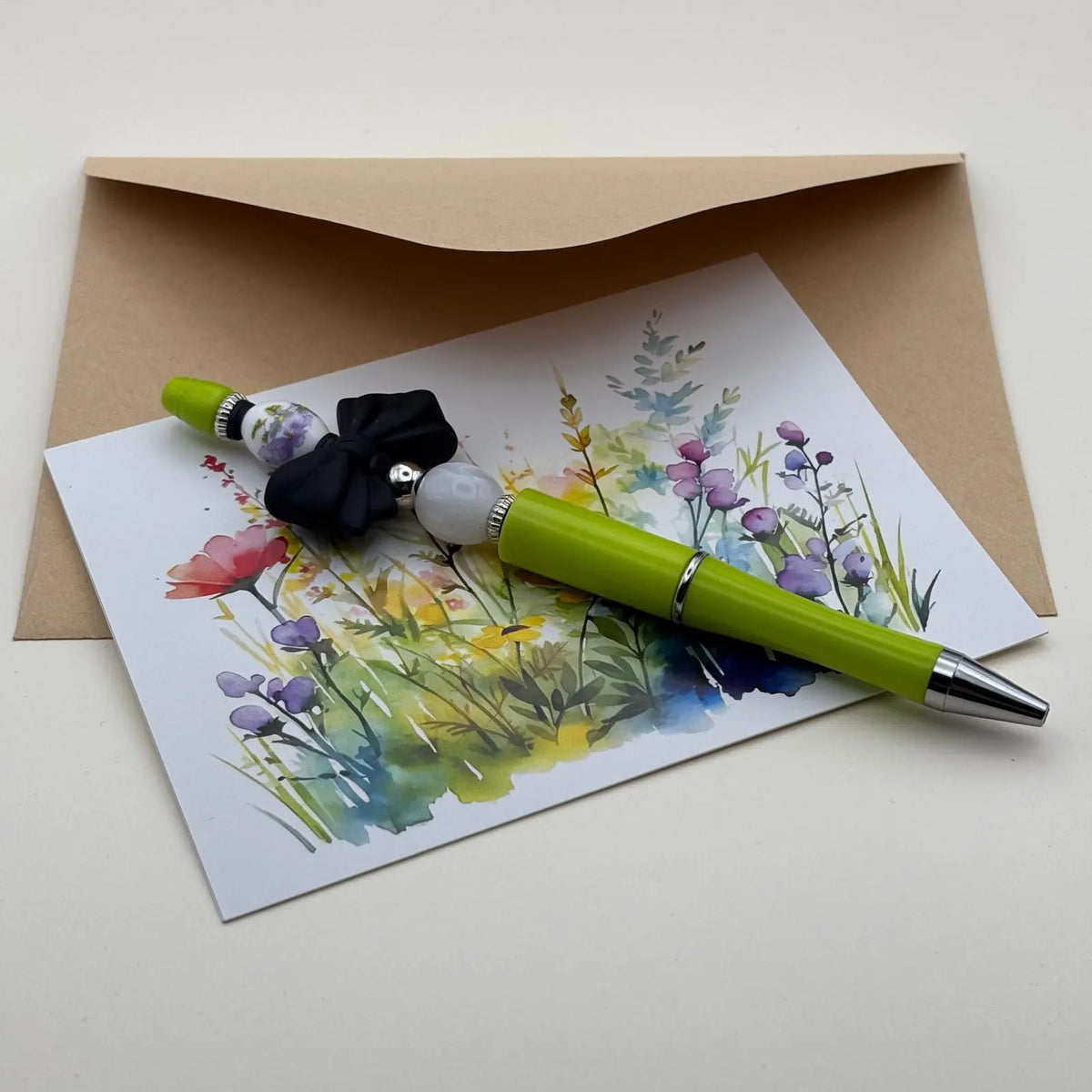 Stylo corps jaune à bille noire rétractable avec des perles couleur blanc nacré et noeud noir