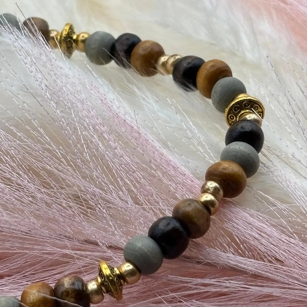 Vue de près d'un bracelet en perles artisanal avec perles ethniques dorées et perles de bois sur élastique