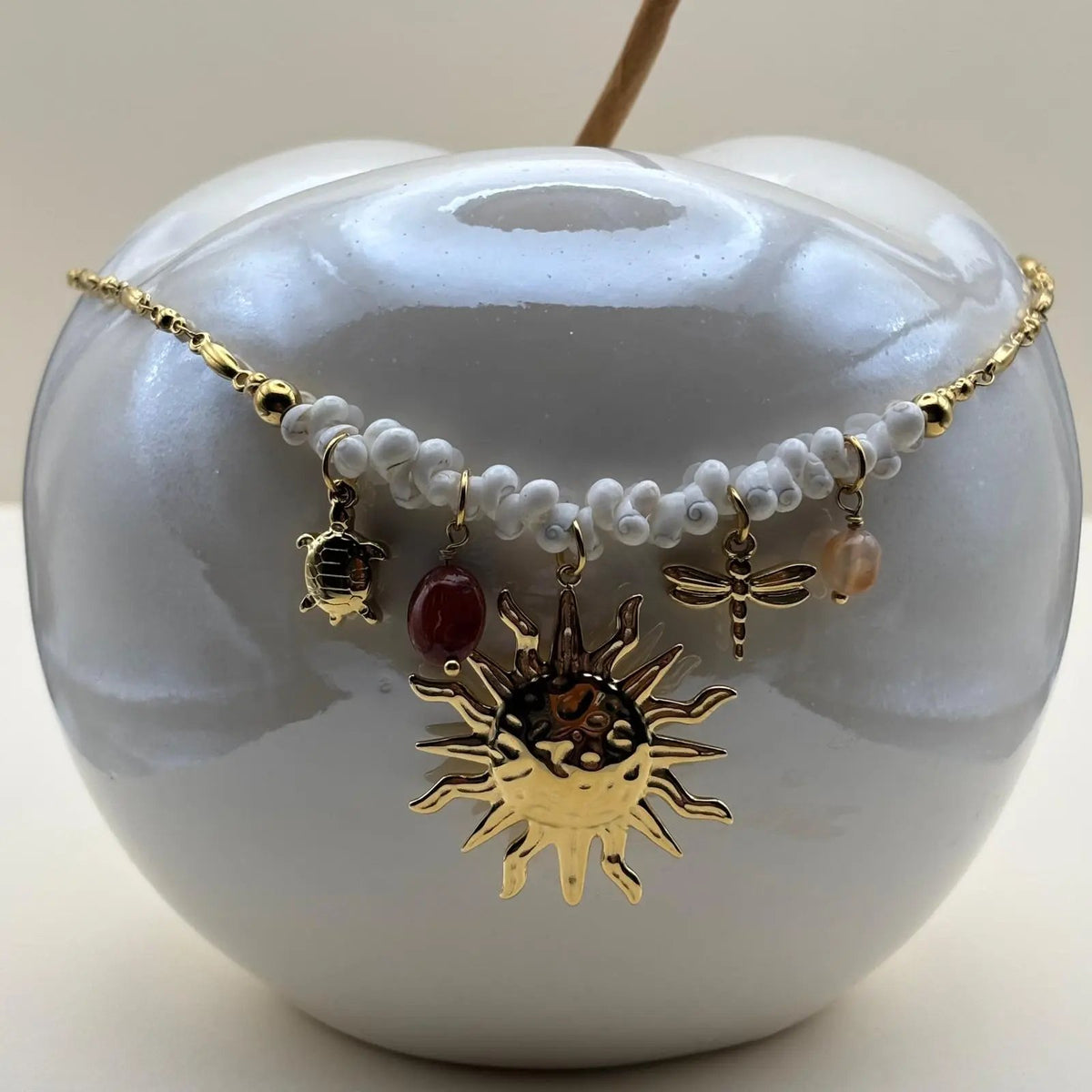 Un collier fantaisie avec un  pendentif et breloques soleil perles tortue libellule petit coquillage de mer blanc