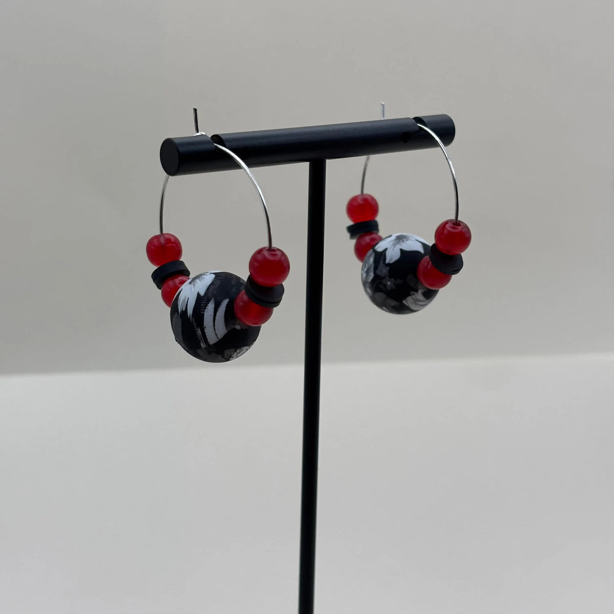 Boucles d'oreilles créoles argentées avec un grosse perle noire et blanche et de petites perles rouges v