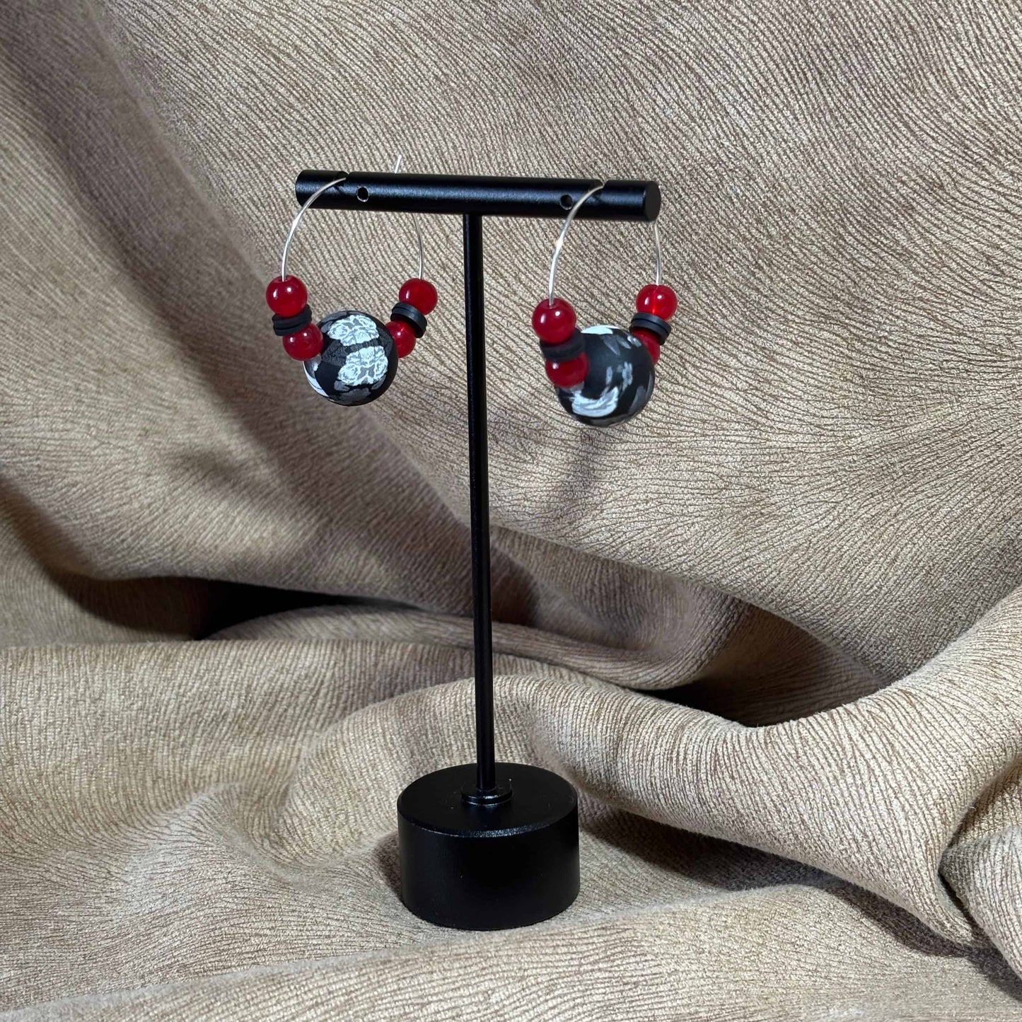 Boucles d'oreilles créoles argentées avec un grosse perle noire et blanche et de petites perles rouges vendues sur le site internet prêtes à briller