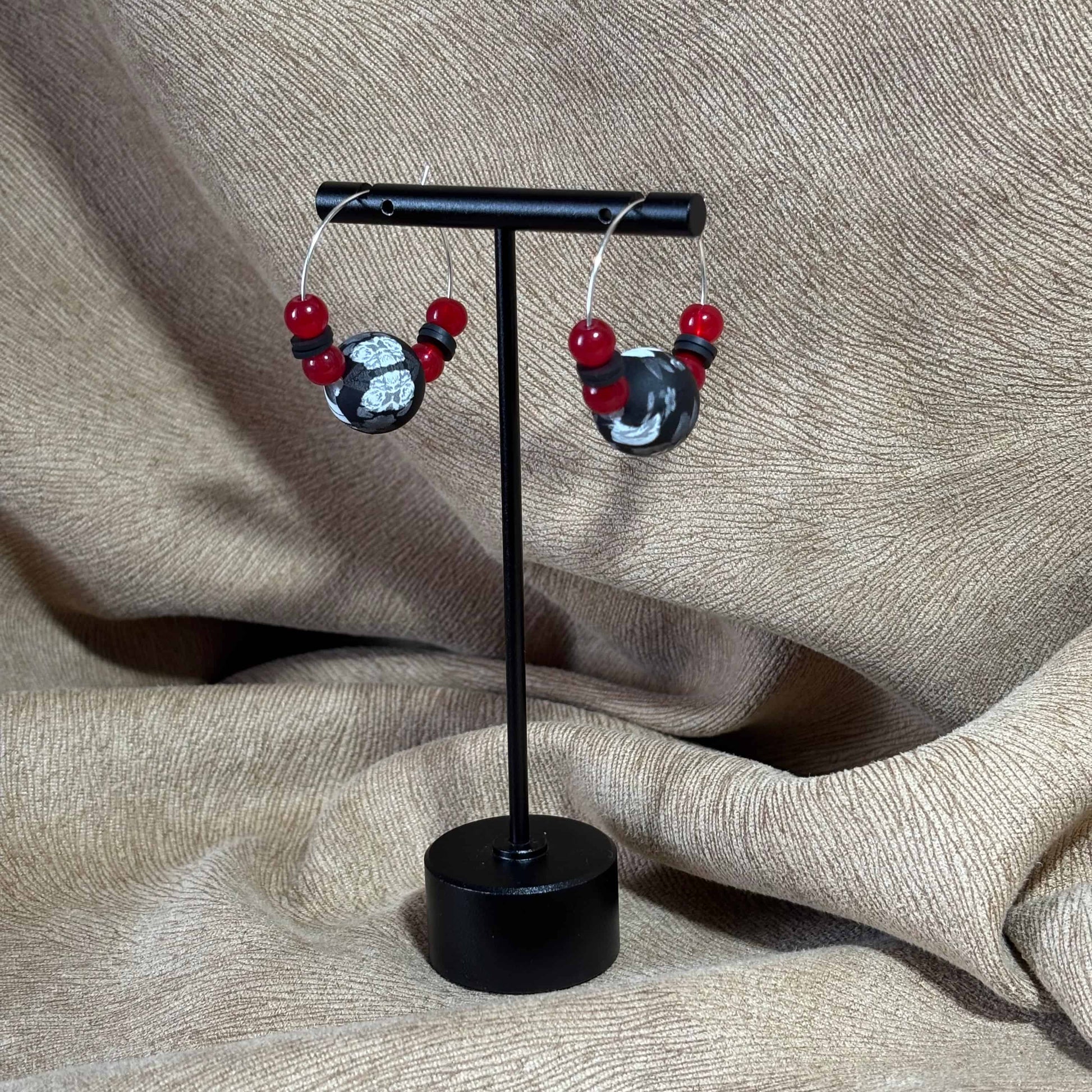 Boucles d'oreilles créoles argentées avec un grosse perle noire et blanche et de petites perles rouges vendues sur le site internet prêtes à briller