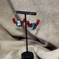 Vue de près de boucles d'oreilles créoles argentées avec un grosse perle noire et blanche et de petites perles rouges vendues sur le site internet prêtes à briller