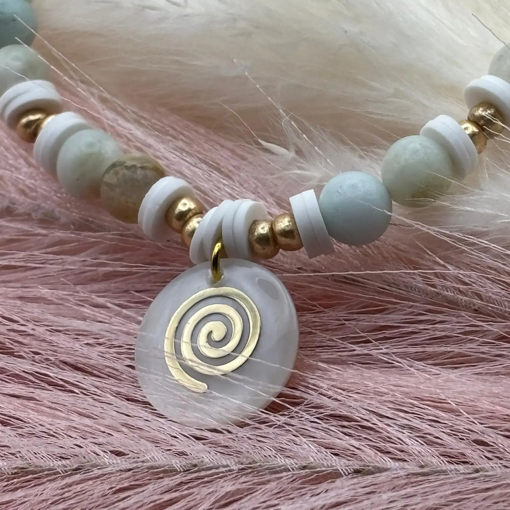 Bracelet en perles artisanal avec breloque pastille en nacre motif tourbillon et perles naturelles pastels sur élastique