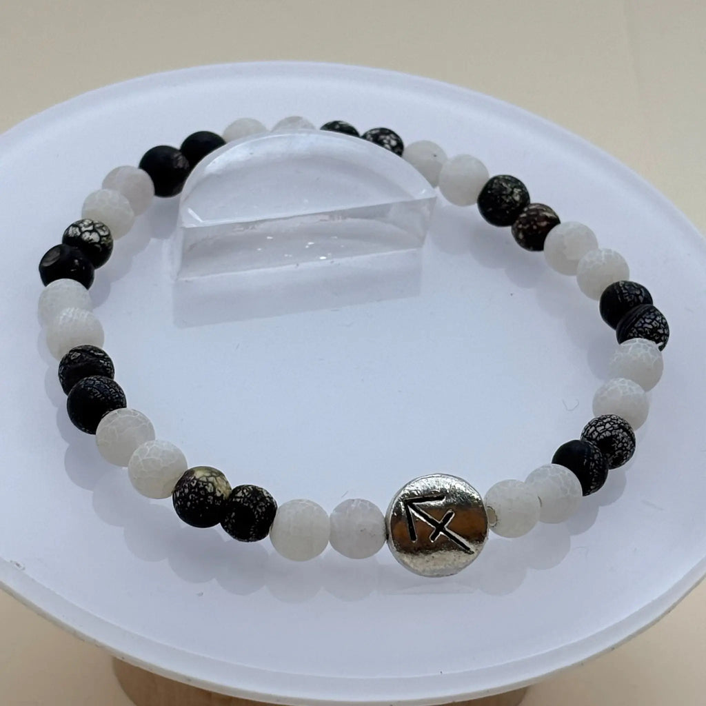 Bracelet composé de perles blanches et noires contrastées rehaussé d’un médaillon argenté gravé