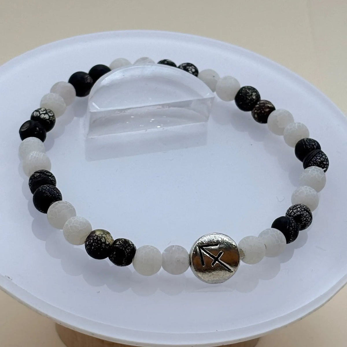 Bracelet composé de perles blanches et noires contrastées rehaussé d’un médaillon argenté gravé