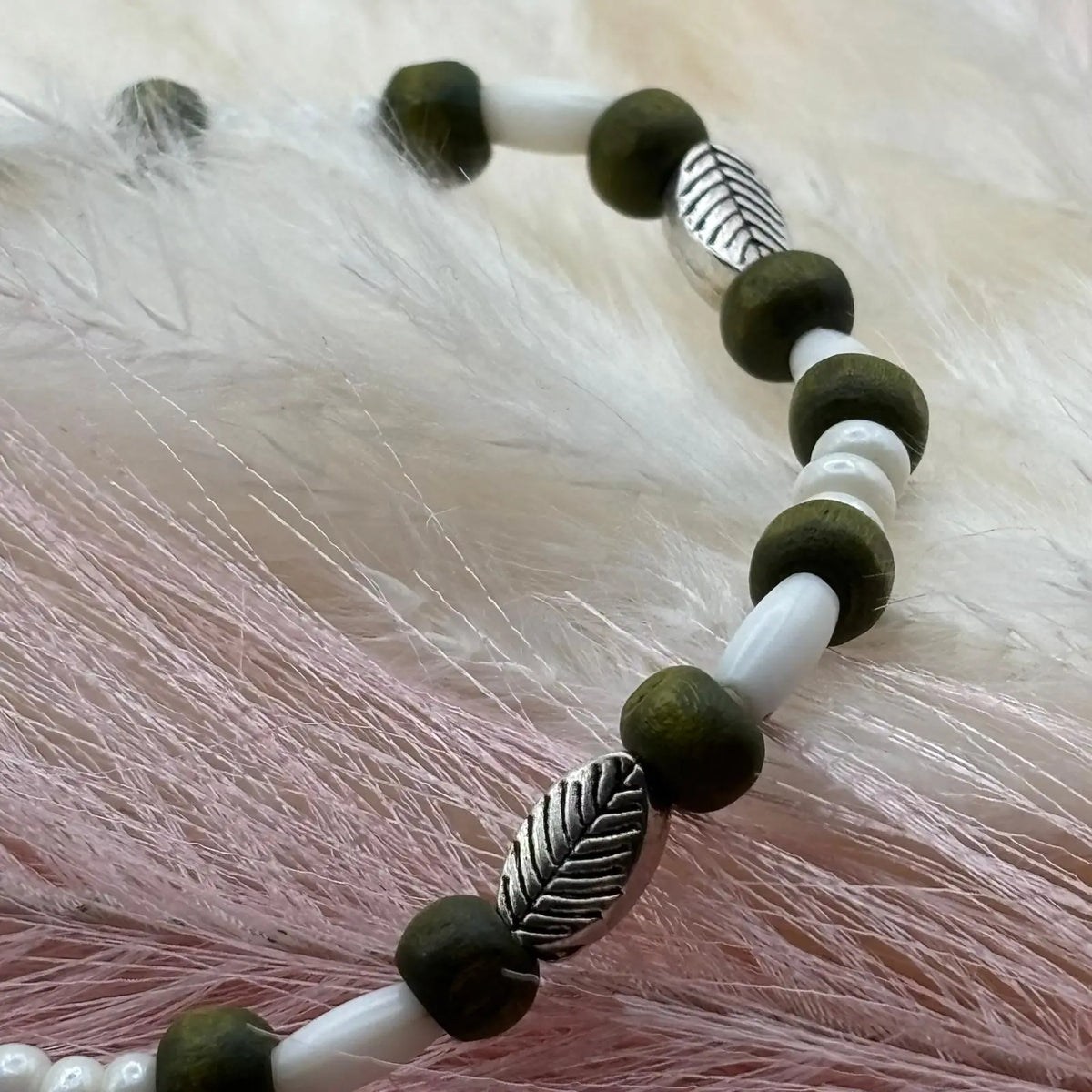 Vue de près d'un bracelet en perles artisanal avec des perles feuilles argentées et en bois sur élastique