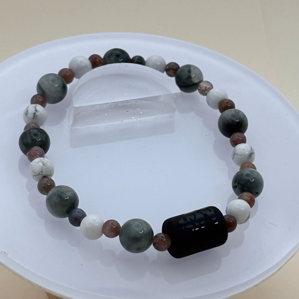 Bracelet alternant perles grises, blanches et brunes avec un cylindre noir gravé en élément central