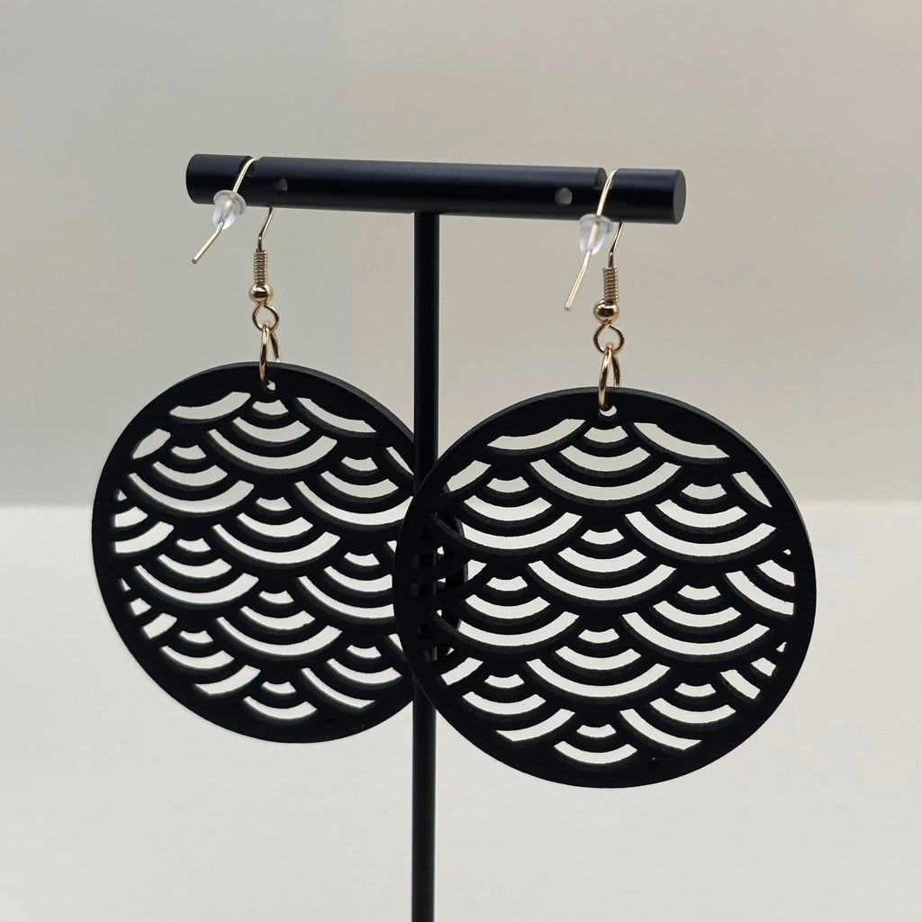 Des boucles d'oreilles avec attache dorée boucle en bois de forme ronde et motif ajouré écailles