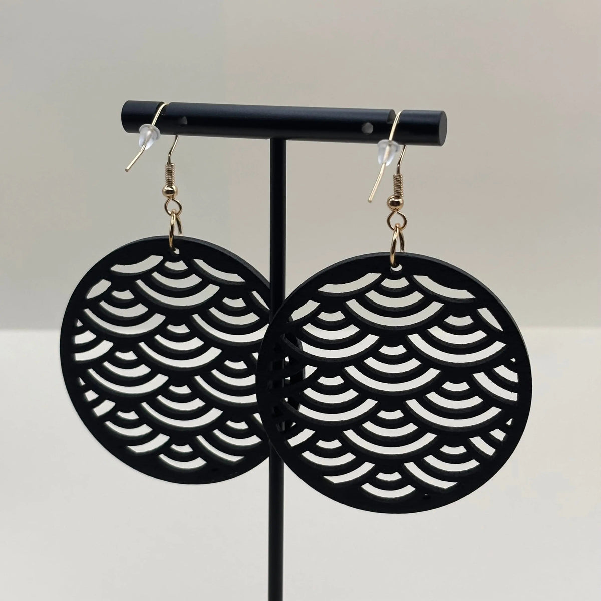 Des boucles d'oreilles avec attache dorée boucle en bois de forme ronde et motif ajouré écailles