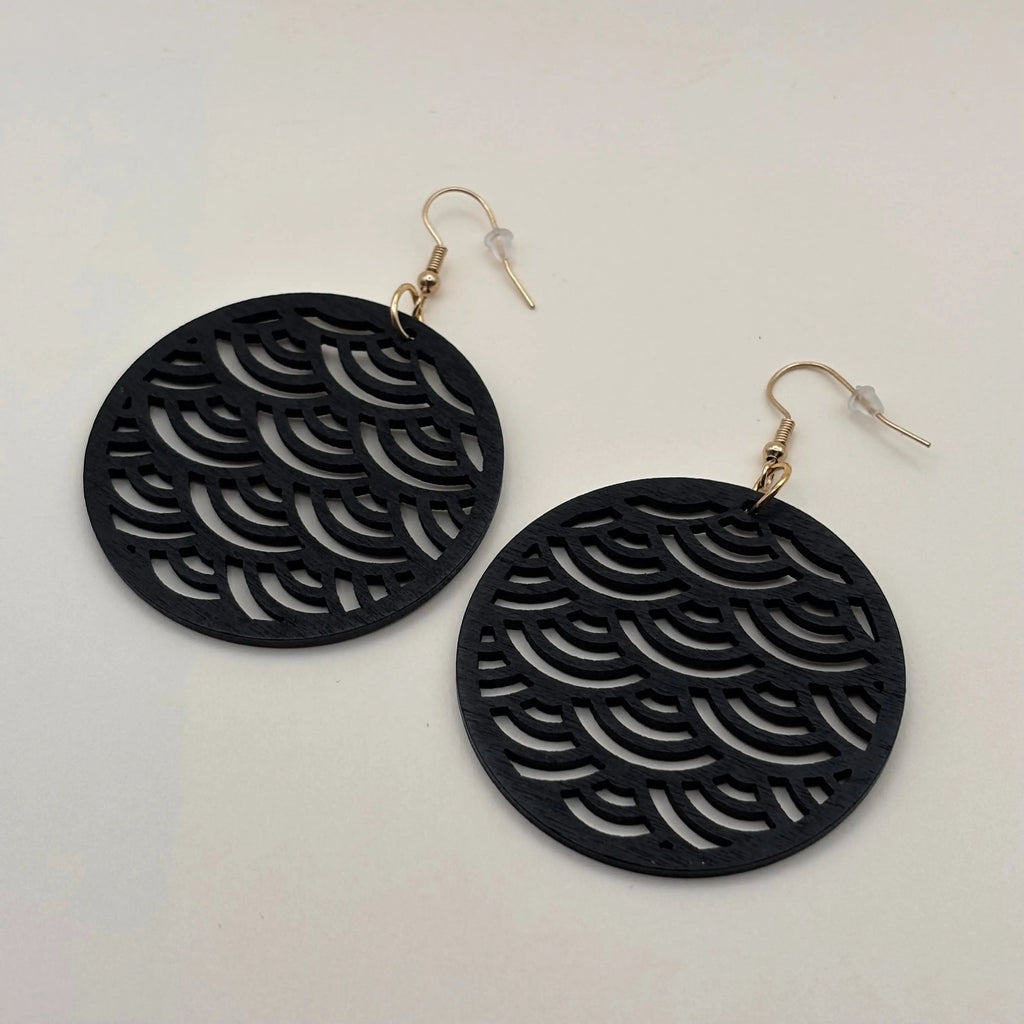 Une paire de boucles d'oreilles avec attache dorée boucle en bois de forme ronde et motif ajouré écailles