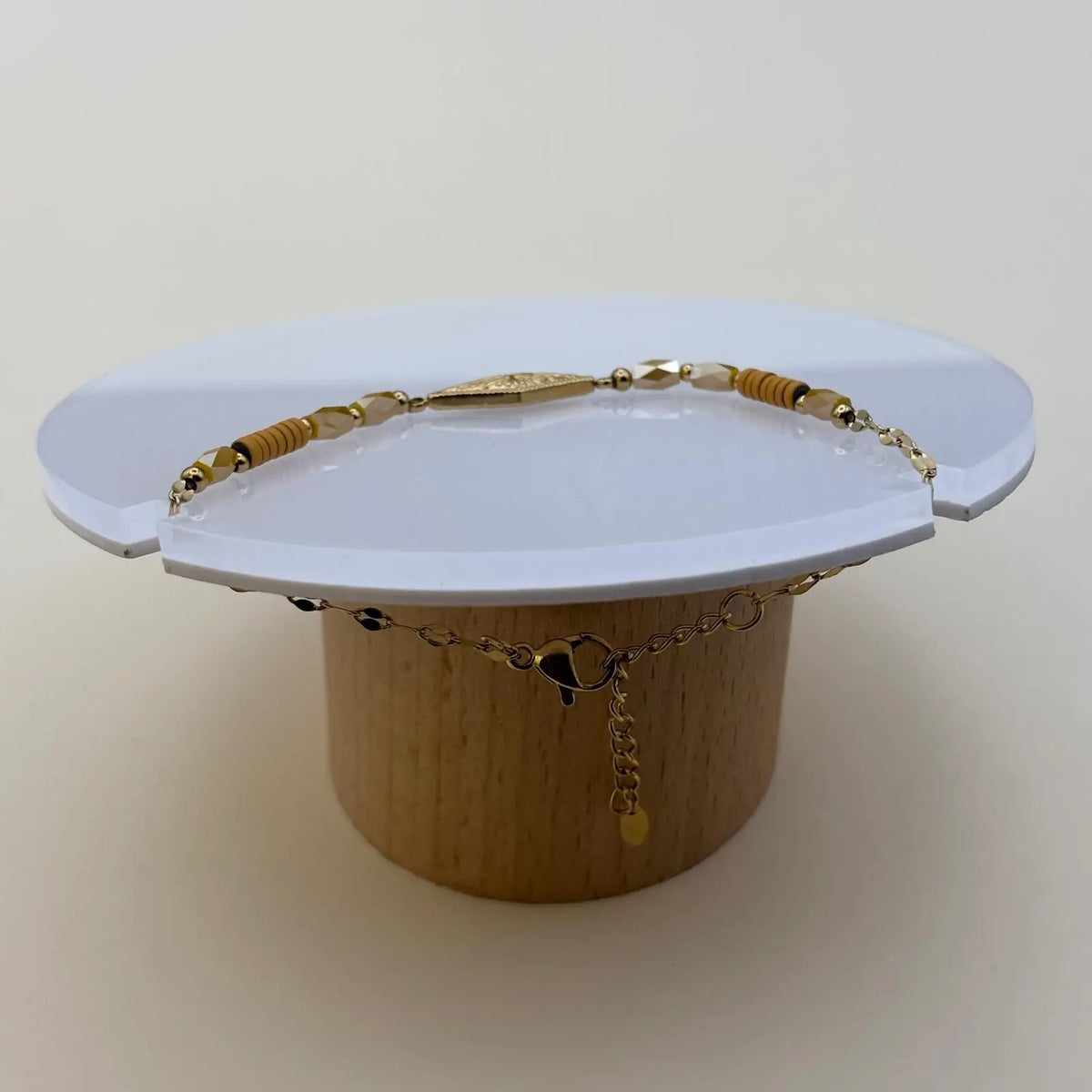 Bracelet doré à mailles fines avec des perles saumon et un motif rose des vents dans un losange doré