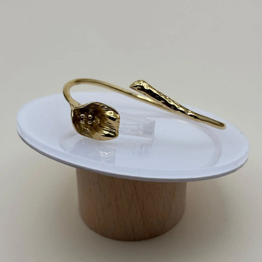 Vue de près d'un bracelet doré rigide ouvert avec un motif fleur d'arum dorée