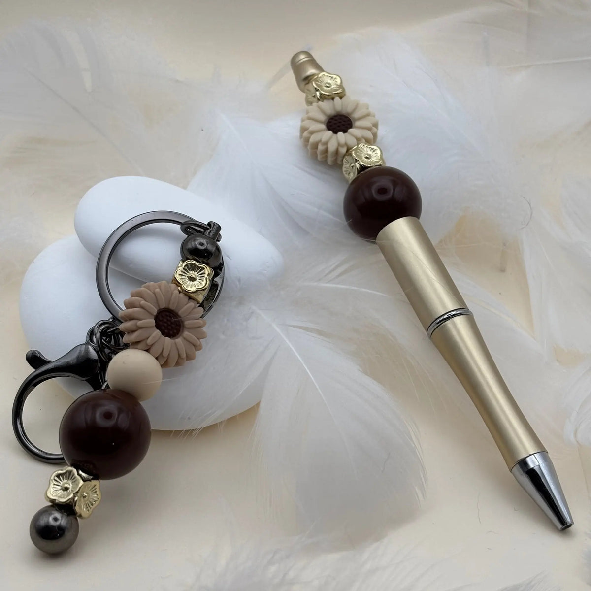 Stylo doré décoré de fleurs crème et perles marron, accompagné d’un porte-clés coordonné avec perles beige et marron