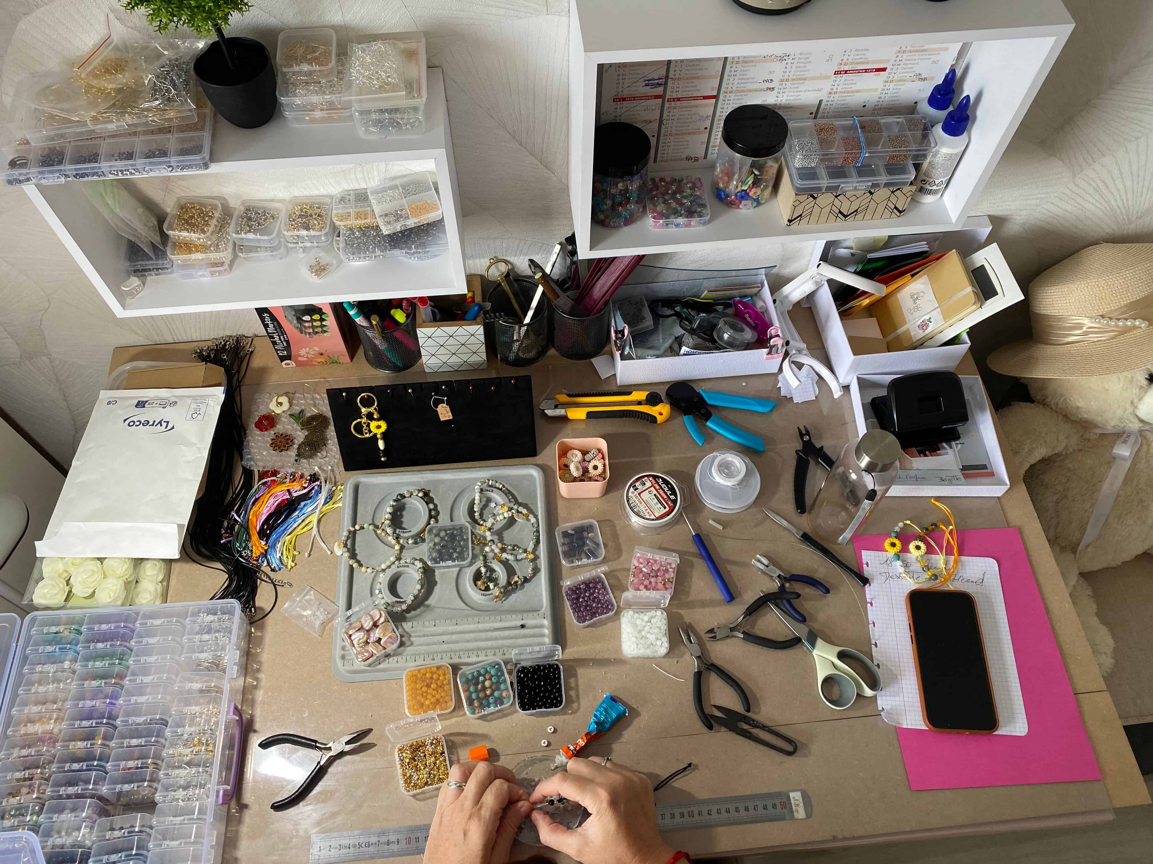 Table de travail  pour la création de bijoux avec outils, perles et mains à l’œuvre site prêtes à briller Image